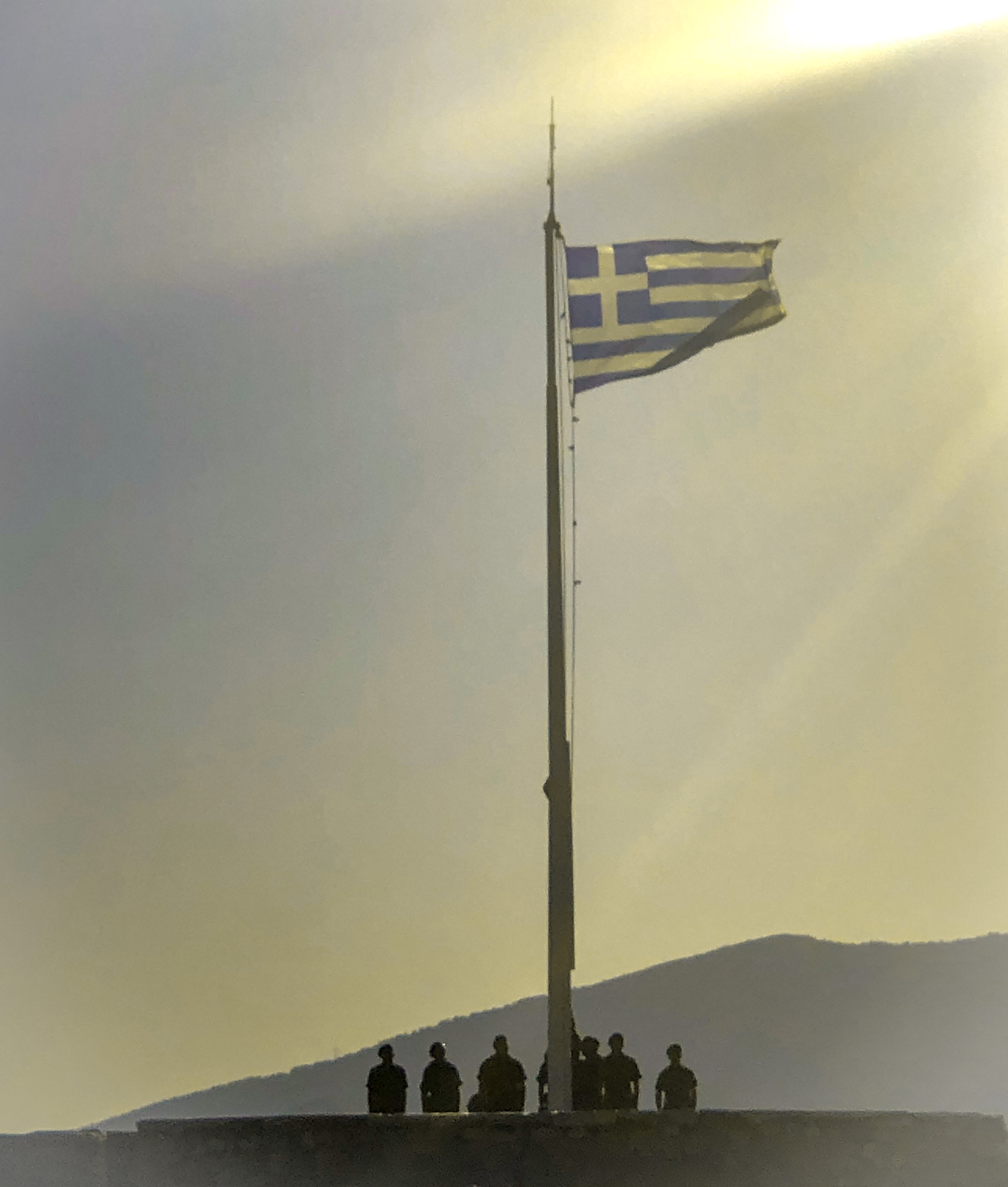 The Greek flag being raised by soldiers in the early morning at the Acropolis, near the Parthenon in Athens, Greece.