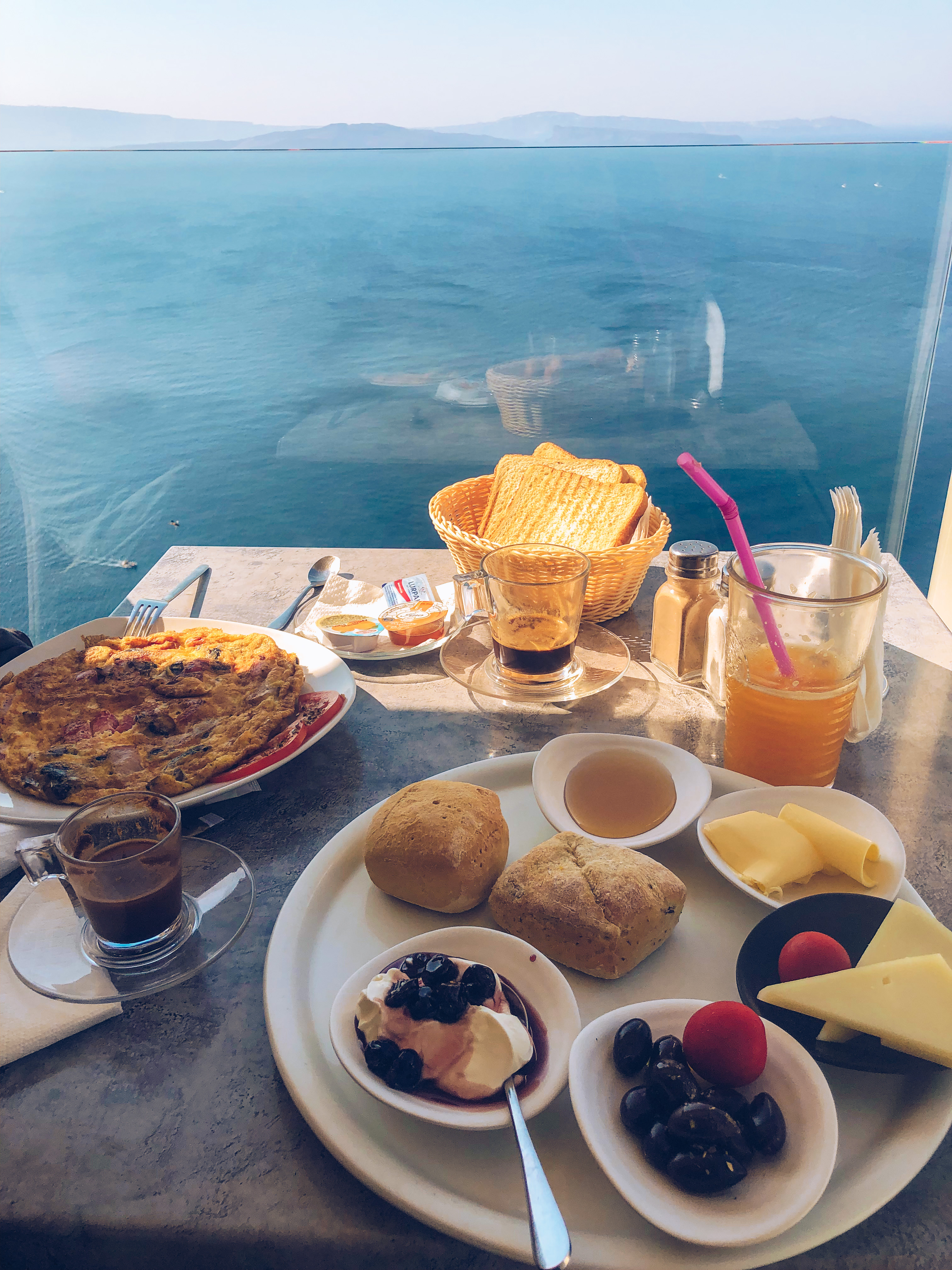 A table at Skiza Cafe with a traditional Greek breakfast, overlooking the caldera in Oia, Santorini.