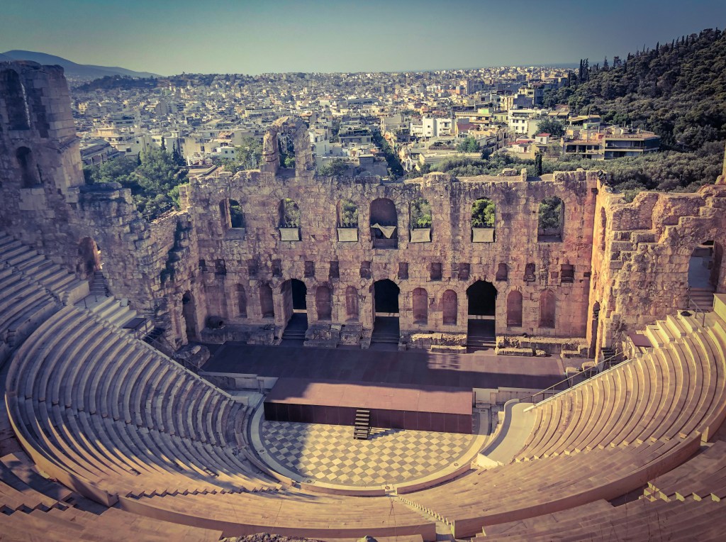 Odeon of Herodes Atticus, an ancient stone theatre, at the Acropolis with the city of Athens in the background.